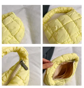 Detail shot of yellow quilted cloud underarm bag showing texture, zipper, and inner pocket structure.