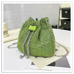 Vue détaillée du sac seau en strass vert scintillant avec bandoulière chaîne et cordon de serrage.
