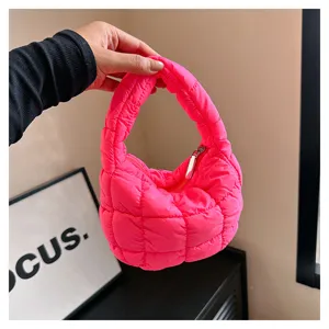 Detailed view of bright pink quilted mini cloud handbag, modern puffy handle texture.
