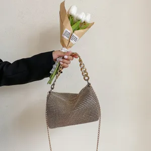 Close-up detail shot of a sparkling rhinestone evening handbag featuring chunky and fine gold chains.