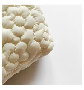 Detail view of white quilted floral cosmetic pouch, soft padded texture for daily travel use.