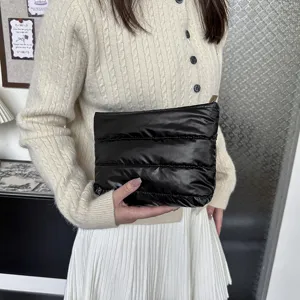 Detail view of the black quilted puffer clutch bag, featuring soft minimalist design.