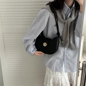 Minimalist black underarm bag for women, chic hobo dumpling handbag with metal lock detail.