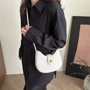 Detailed view of the stylish white hobo shoulder bag with chic gold turn-lock flap closure.