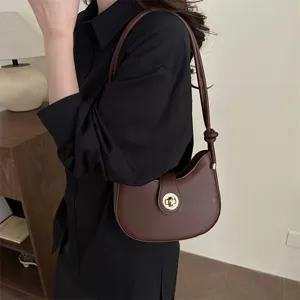 Brown crescent shoulder bag with metal turn-lock closure, stylish underarm dumpling bag.