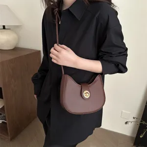 Detail view of stylish brown leather underarm shoulder bag featuring a sleek metal lock.