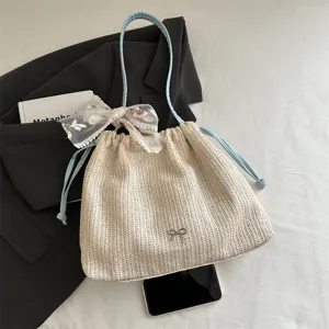 Detail shot of straw woven shoulder bag with blue drawstring, lace bow, and elegant daily styling.