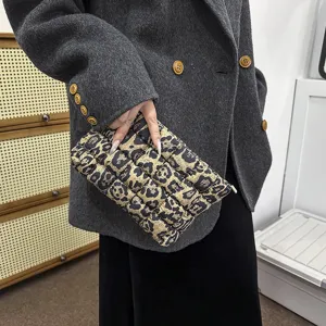 Detail van gewatteerde nylon clutch tas met luipaardprint, zachte textuur en ritsluiting.