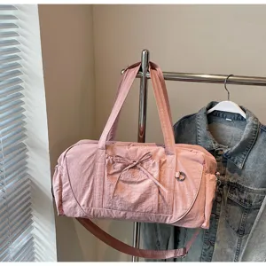 Pink sports duffel bag detail showing front bow, embroidery and sturdy shoulder strap hardware