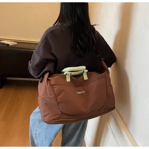 Detailed shot of a large capacity travel duffel bag in brown with green handles worn.