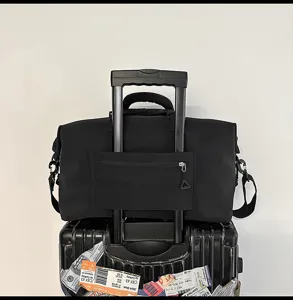Detail view of black travel duffel bag with trolley sleeve and secure zipper pocket, travel setup.