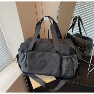 Close-up detail of black travel duffel bag showing grid side pockets and sturdy handles.