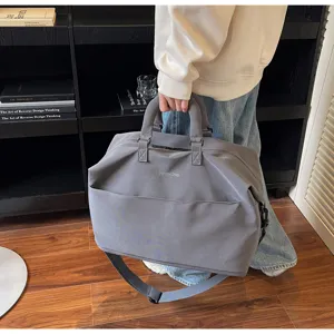 Détail de sac de voyage gris, grand sac de sport avec poignée et bandoulière réglable.