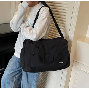 Detail view of large capacity black travel duffel bag, casual shoulder strap gym style.