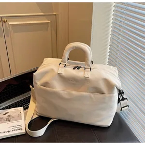 Detail view of the beige canvas travel duffel bag with handles and shoulder strap in lifestyle setting.