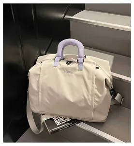 Detailed close-up view of the spacious canvas travel duffel bag in beige with purple handle.