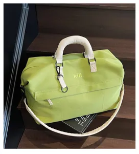 Detail view of a large capacity travel duffel bag in light green with white handles and strap.
