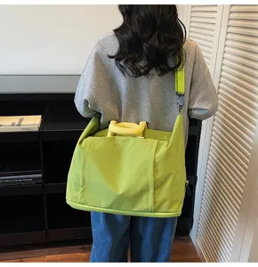 Detail view of large capacity travel duffel bag with shoulder strap and yellow handles.
