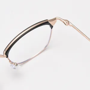 Close-up details of vintage metal half-frame glasses, retro black and gold design.