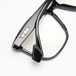 Close-up detail shot of stylish black optical glasses frame with metallic temple emblem.
