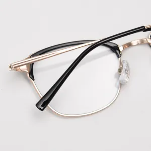 Close-up detail of retro metal half-frame glasses frame in gold and black, elegant.