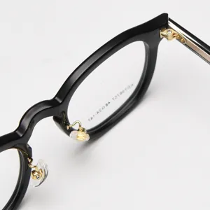 Detailed shot of retro thick-rim black acetate optical eyeglasses frame with gold metal details.