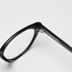Close-up detail of black eyeglasses frame hinge and temple design, sleek minimal style.