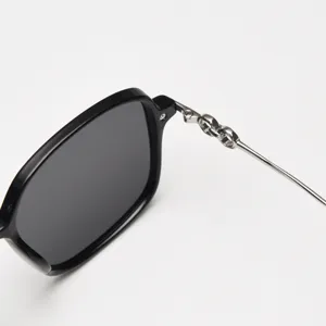 Close-up of stylish black frame sunglasses featuring metallic chain link temple details.