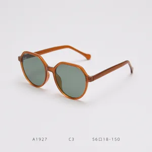 Modische polygon Sonnenbrille für Damen mit bernsteinfarbenen Gestellen und grünen Gläsern.