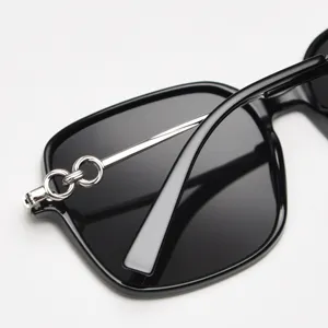 Close-up of black oversized polarized sunglasses with silver metal chain temple detail.