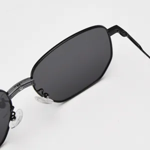 Black metal polygon sunglasses frame detail view, polarized dark lens, stylish street style accessory.