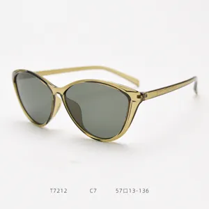 Retro cat-eye sunglasses detail view, translucent olive frame and dark grey lenses.