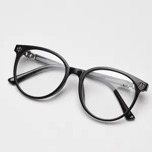 Close-up of black round eyeglasses frame with delicate silver floral temple details for stylish look.