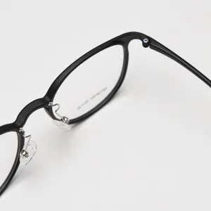 Close-up detail of black matte round glasses frame, showing hinge and nose pad design.