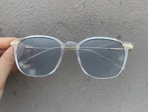 Detail view of transparent square frame sunglasses with metal temples and tinted lenses.