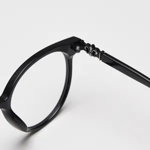 Detailed close-up view of a black round eyeglass frame featuring a stylish silver hinge accent.