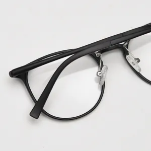 Close-up of black retro round eyeglass frame detail showing metal nose pads and sleek design.