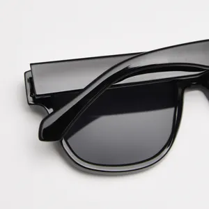 Detailed close-up of trendy black thick frame polarized sunglasses with retro design.