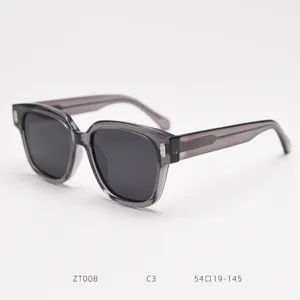 Detail shot of translucent grey chunky frame sunglasses with black lenses and metal rivets.