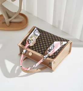 Primo piano dettagliato di borsa da donna con motivo monogramma e sciarpa di seta.
