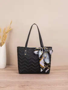 Detailansicht der schwarzen gesteppten Tasche mit edlem Schal und doppelten Henkeln.
