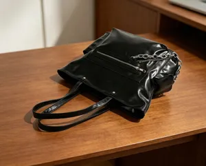 Vue détaillée du sac cabas minimaliste noir, avec décoration de chaîne métallique et poche zippée.