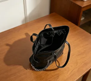Vue détaillée du sac cabas en cuir noir avec chaîne argentée, grand espace et poches.