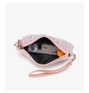 Detail view of a stylish pink tweed clutch bag showing inner capacity and metal details.
