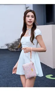 Detailed view of a chic tweed crossbody handbag with pink pattern and elegant wrist strap.