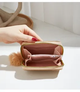 Detailed view of women short wallet with zipper closure and cute fluffy pom pom charm accessory.