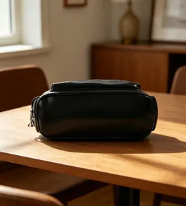 Gros plan détaillé d'une pochette minimaliste en cuir noir sur table en bois et texture.
