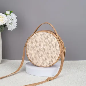 Vista dettaglio borsa tracolla paglia rotonda, borsa estiva tessuta con finiture pelle.