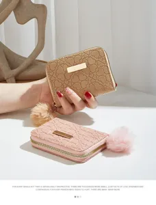 Close-up detail of compact women short wallet with heart debossed pattern and plush pom-pom.