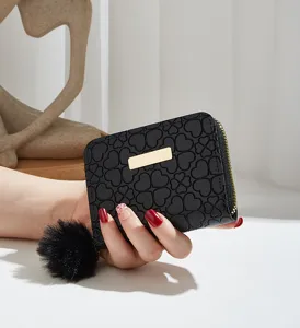 Black short wallet with clover embossing and chic pom-pom detail. Premium compact coin purse.